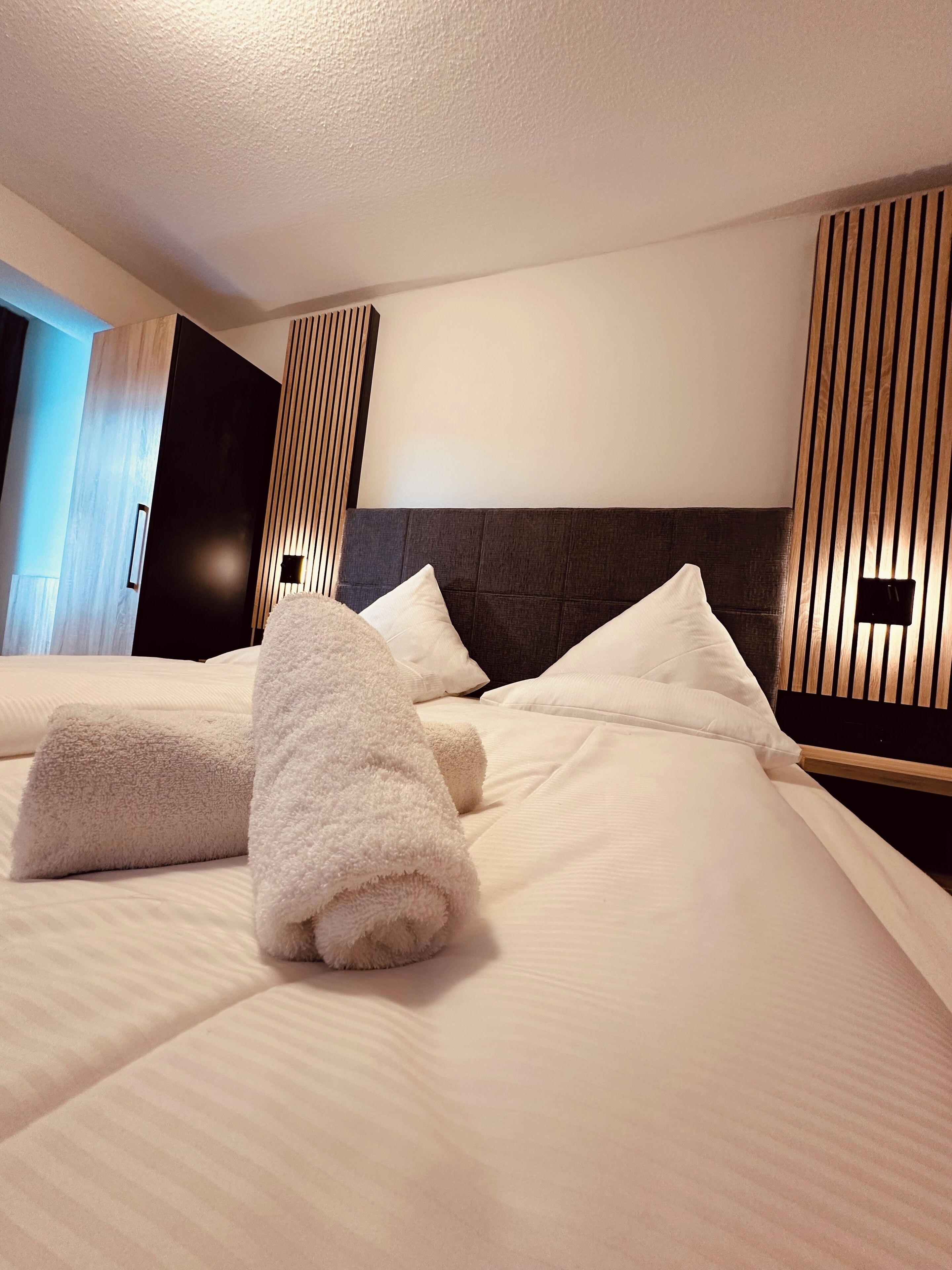 Habitación de hotel con una cama grande, cabecera de madera y diseño moderno.
