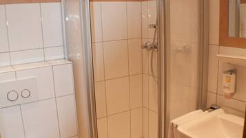 Ein modernes Badezimmer mit einer Duschkabine, einer weißen Toilette und einem Waschbecken mit Spiegel darüber.