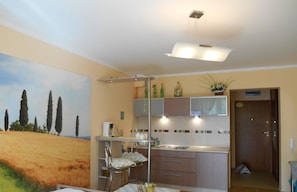 Une cuisine de taille réduite avec un coin repas, un luminaire au plafond et une porte donnant sur une autre pièce.