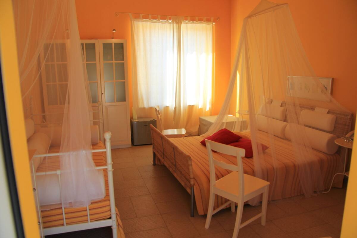 A bedroom with a canopy bed, a desk, and a chair.