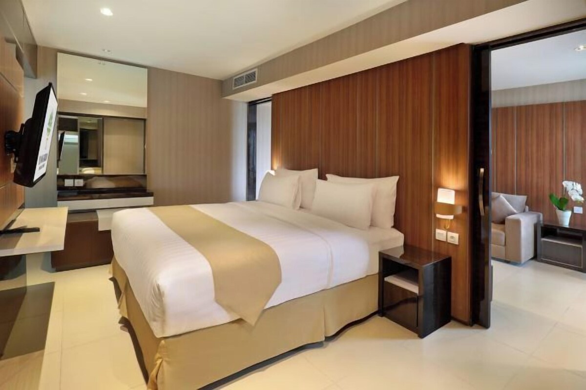Een moderne hotelkamer met een groot bed, een nachtkastje, een televisie en een spiegel.
