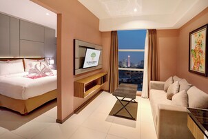 A hotel room with a bed, a sofa, a TV, and a city view.