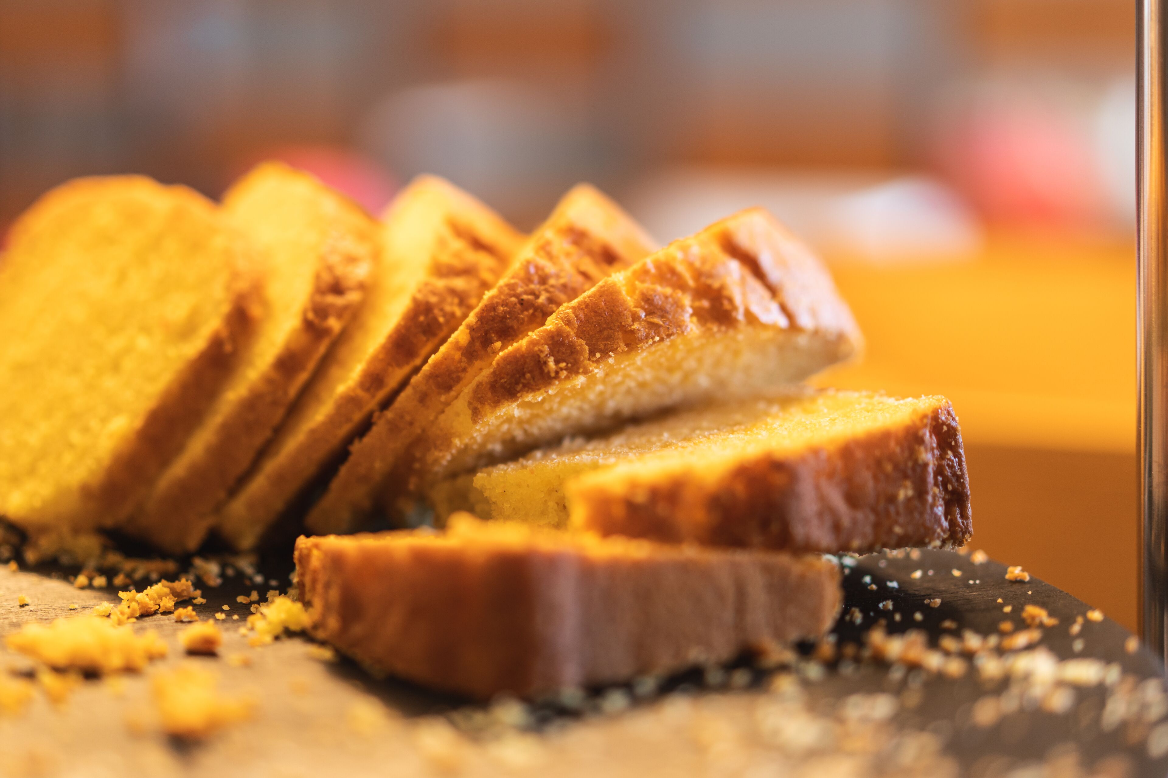 A close-up of sliced bread with crumbs on a dark surface.