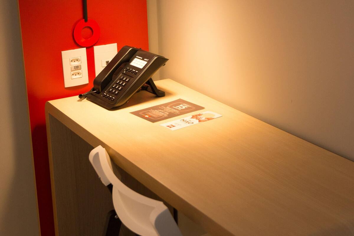 A desk with a telephone, a chair, and a wall socket.