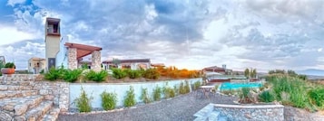 Resort com degraus de pedra que levam a uma área de piscina, rodeada por vegetação exuberante e um céu claro.