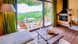 A room with a large sliding glass door leading to a garden, a fireplace, and a dining area with a table and chairs.