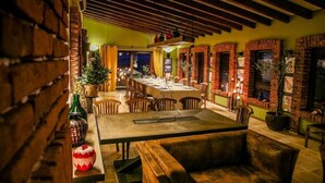A cozy dining area with brick walls, wooden beams, and a long table set for dining. - Zornitza Family Estate (Zornitza)