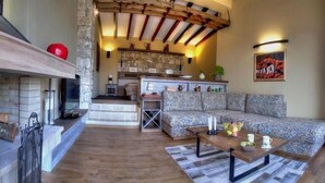 A cozy living room with a fireplace, a patterned sofa, and a wooden coffee table. - Zornitza Family Estate (Zornitza)