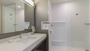 Un baño moderno con lavamanos doble, un espejo grande y cabina de ducha con mampara de vidrio.
