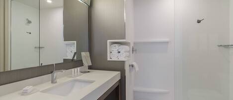 Un baño moderno con lavamanos doble, un espejo grande y cabina de ducha con mampara de vidrio.