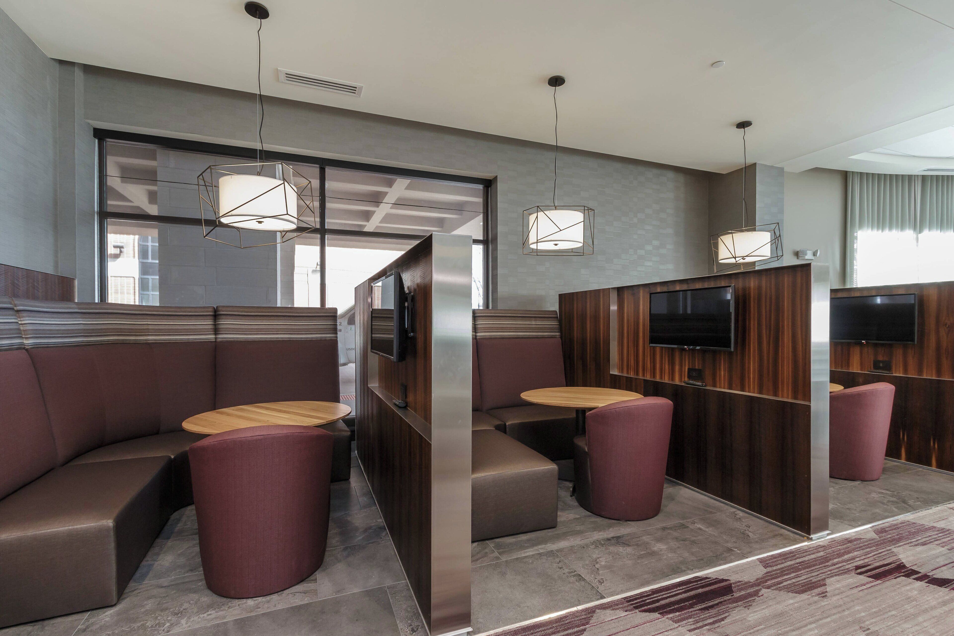 A modern restaurant with booth seating, round tables, and pendant lighting.