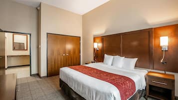 Een hotelkamer met een groot bed, een houten garderobe, een nachtkastje en een spiegel.
