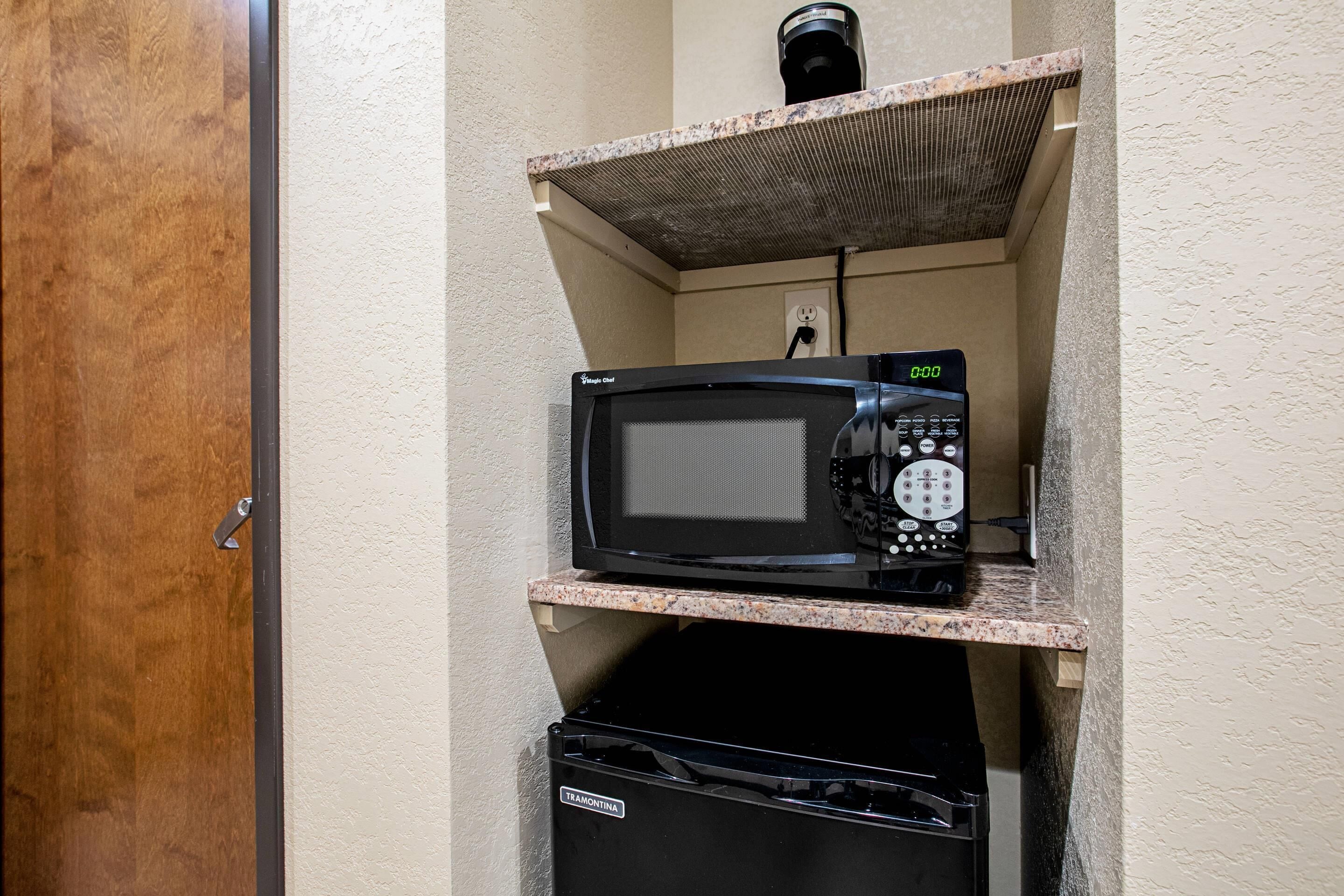 A microwave on a shelf above a dishwasher.