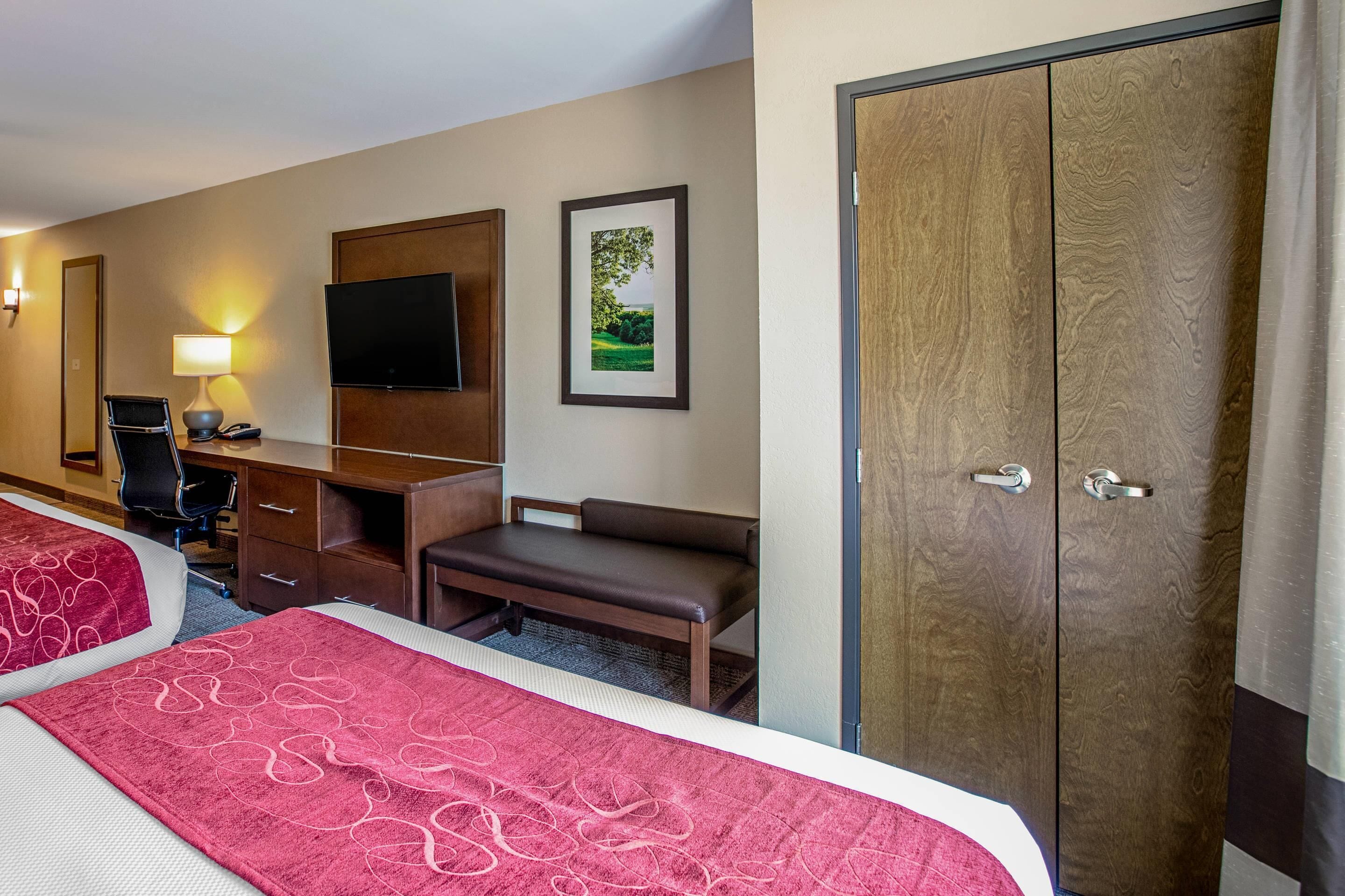 A hotel room with two beds, a desk, a chair, a TV, and a wardrobe.