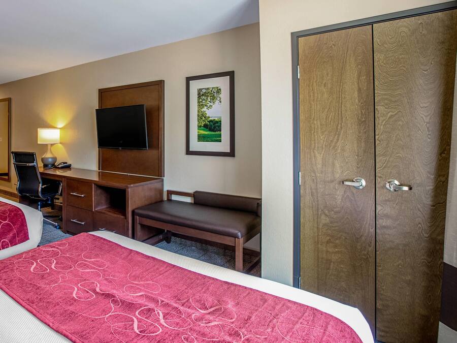 A hotel room with two beds, a desk, a chair, a TV, and a wardrobe.