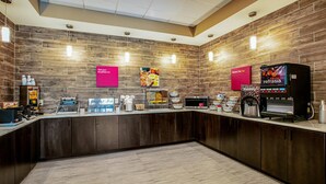 Una barra de desayuno moderna con pared de madera, una máquina de café y un dispensador de zumo.
