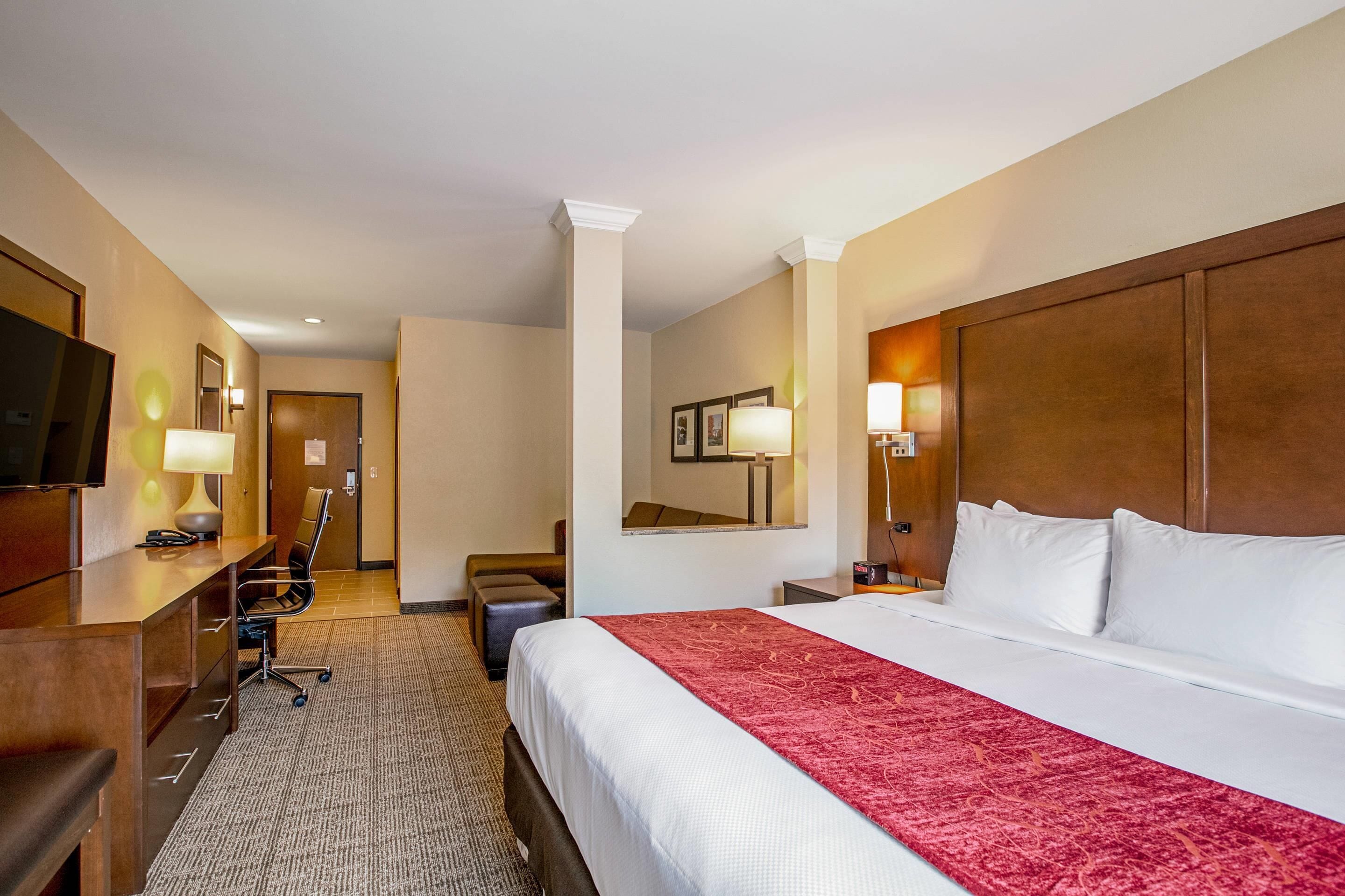 Een hotelkamer met een groot bed, een bureau, een stoel, een televisie en een spiegel.