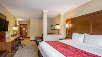 Een hotelkamer met een groot bed, een bureau, een stoel, een televisie en een spiegel.