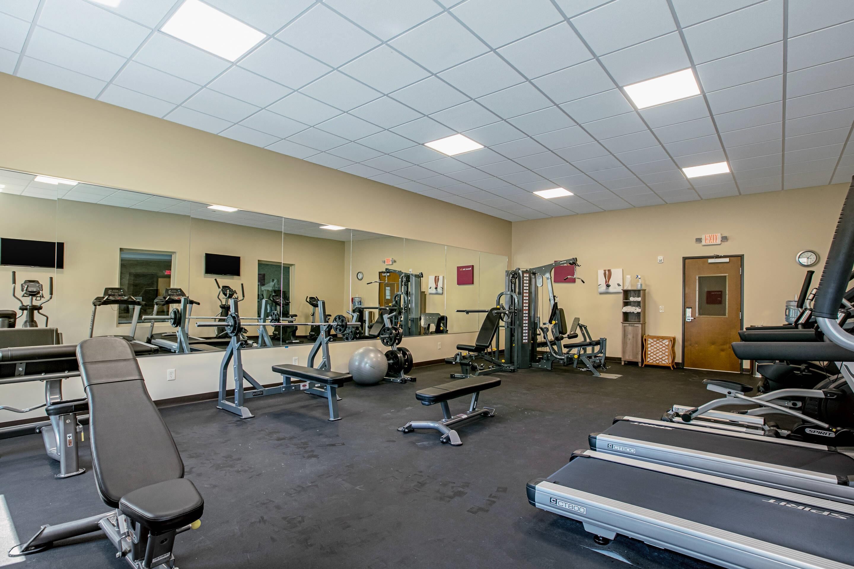 A gym with treadmills, weight machines, and benches.