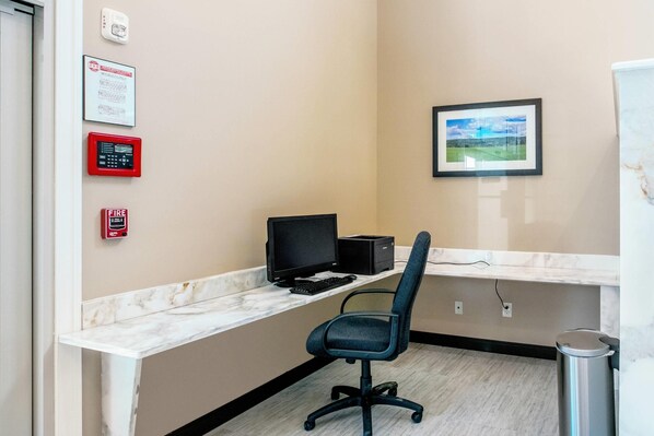 A modern office space with a marble countertop, a black office chair, a computer setup, and a framed landscape picture on the wall.