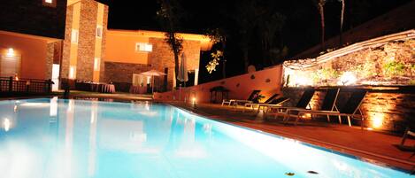 A swimming pool with lounge chairs and a stone wall.