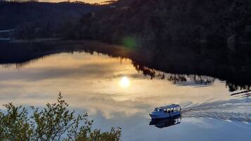 A calm lake with a boat in the foreground and hills in the background.