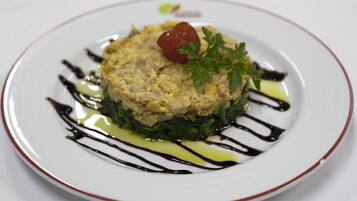 A plate of food with a garnish of parsley and a cherry tomato on top, surrounded by a drizzle of sauce.