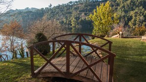 A wooden bridge over a body of water with a forested hillside in the background. - Hotel Rural Quinta da Conchada (Penacova)