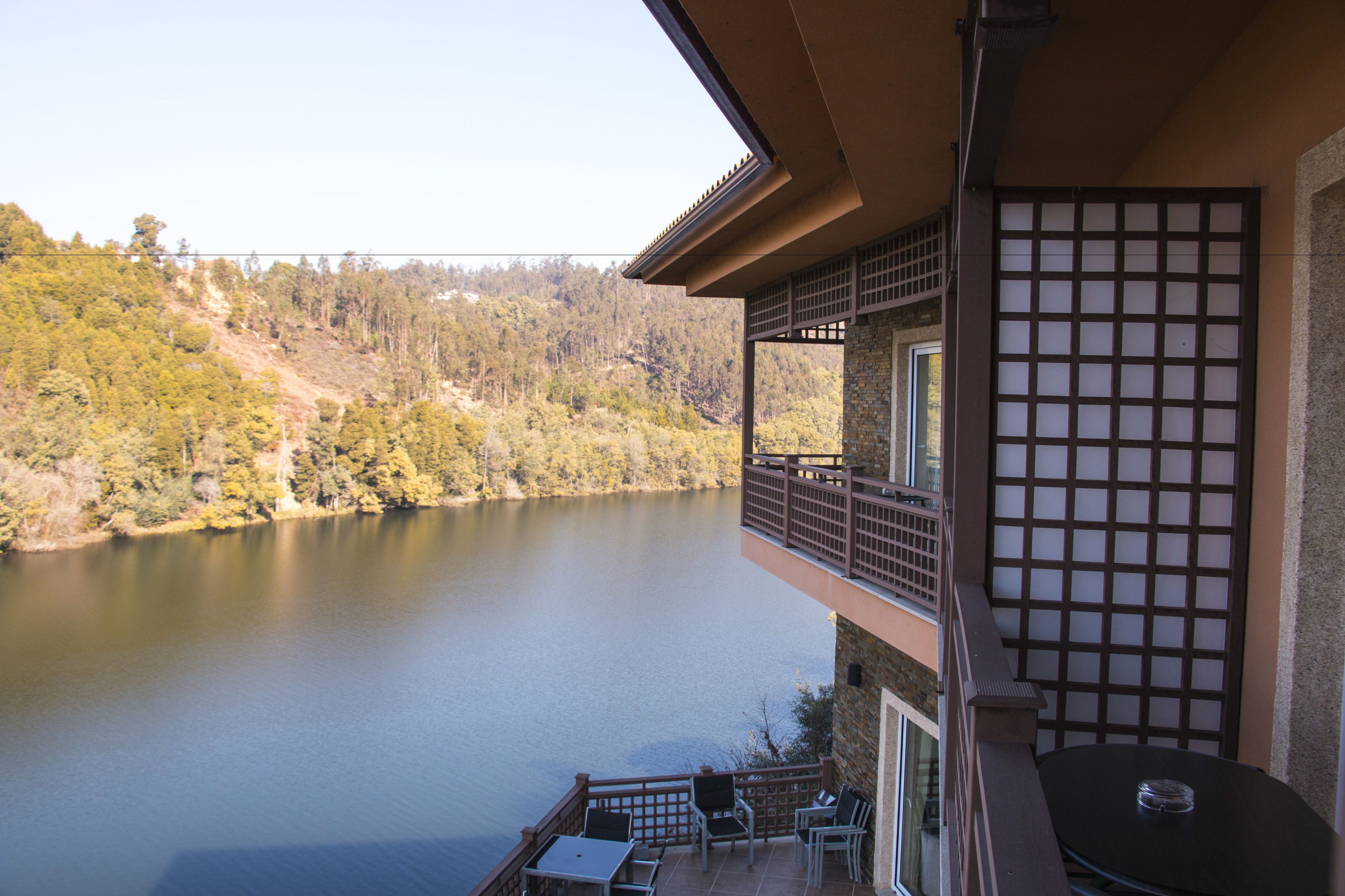 Un balcone con vista su un lago e colline ricoperte di alberi.