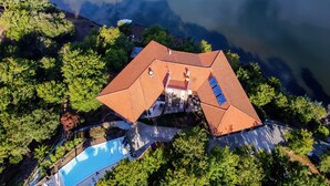 An aerial view of a house with a red roof, surrounded by lush greenery and a swimming pool. - Hotel Rural Quinta da Conchada (Penacova)