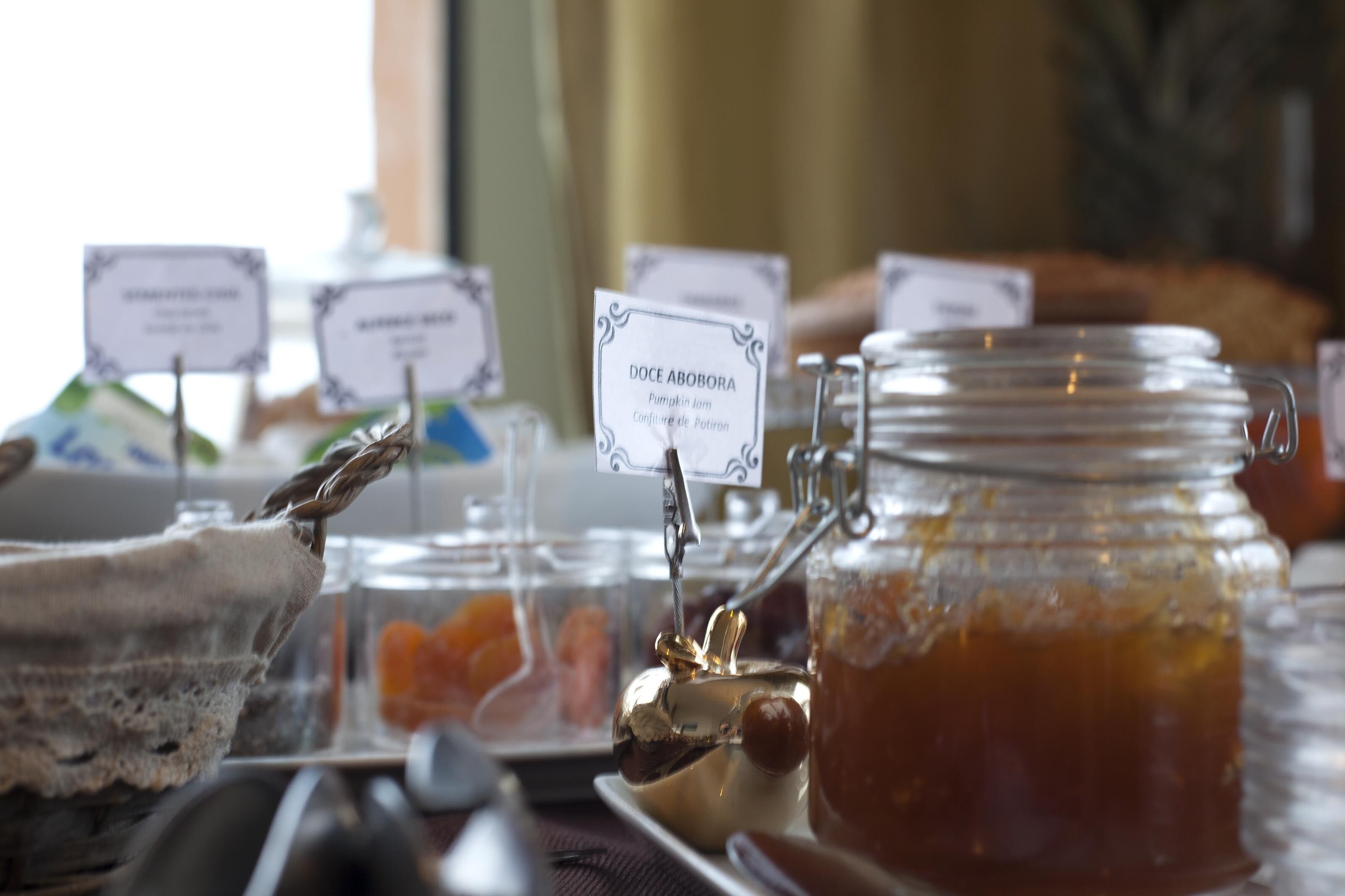 A buffet setup with labeled dishes and a jar of honey.