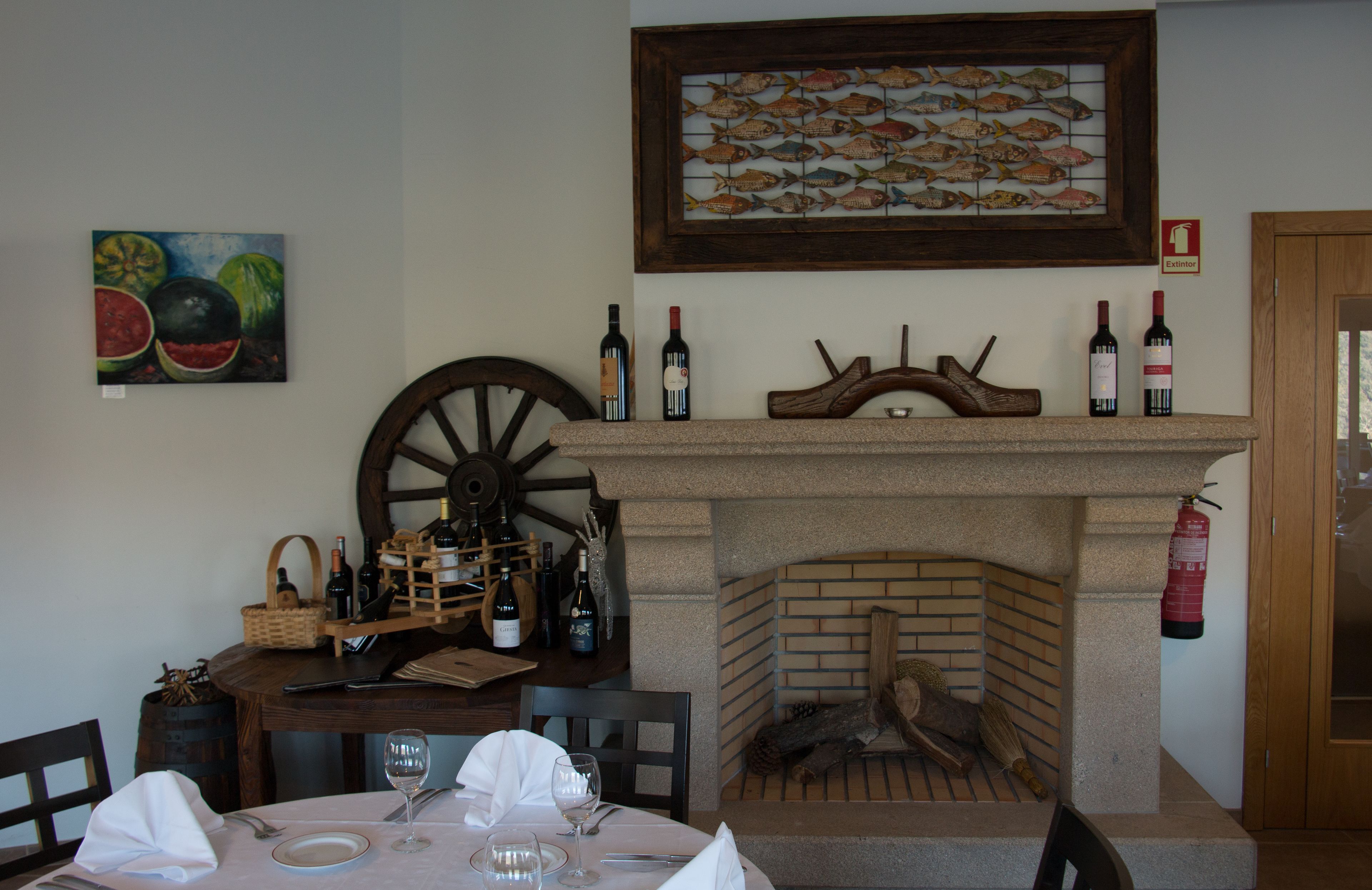 Un comedor con chimenea, botellas de vino y una mesa de madera.