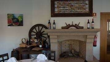 Un comedor con chimenea, botellas de vino y una mesa de madera.