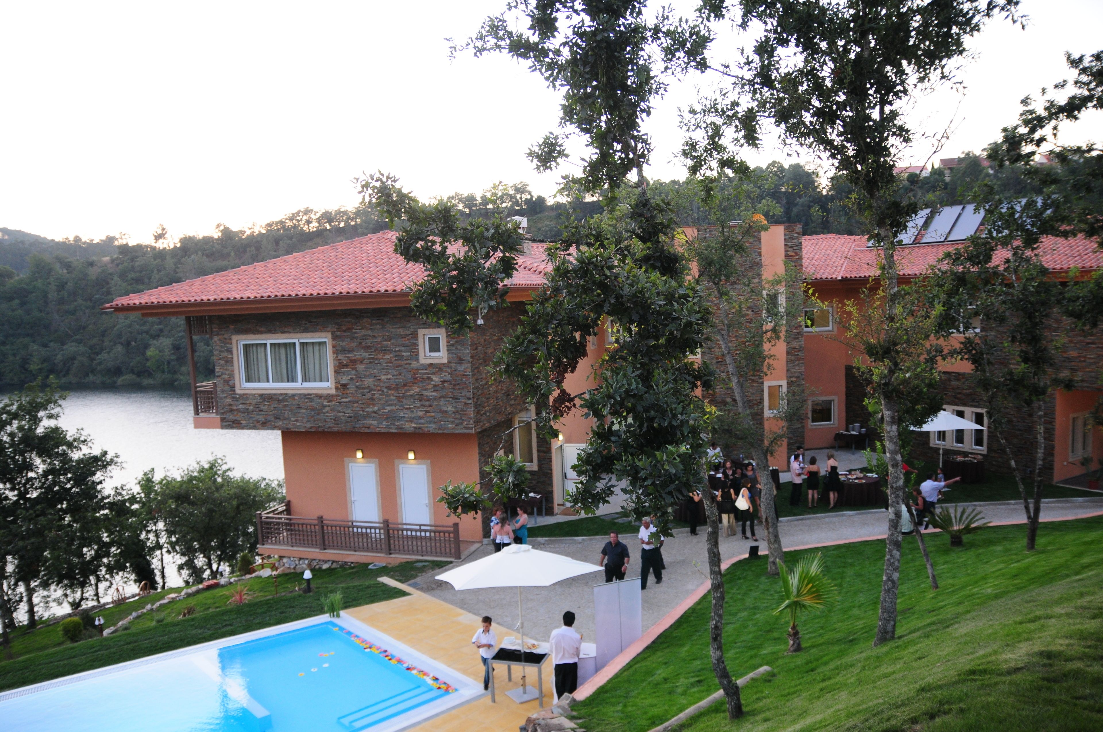 A two-story building with a swimming pool, outdoor seating, and a view of a lake.