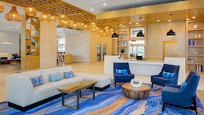 A modern lobby with a sofa, armchairs, a coffee table, and a patterned rug.