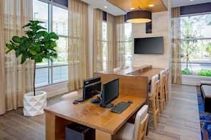 A modern hotel room with a wooden desk, computer, and seating area. - Hyatt House across from Universal Orlando Resort (Orlando)