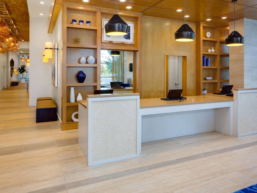 A reception desk with a wooden finish, overhead pendant lighting, and a view of the street outside.