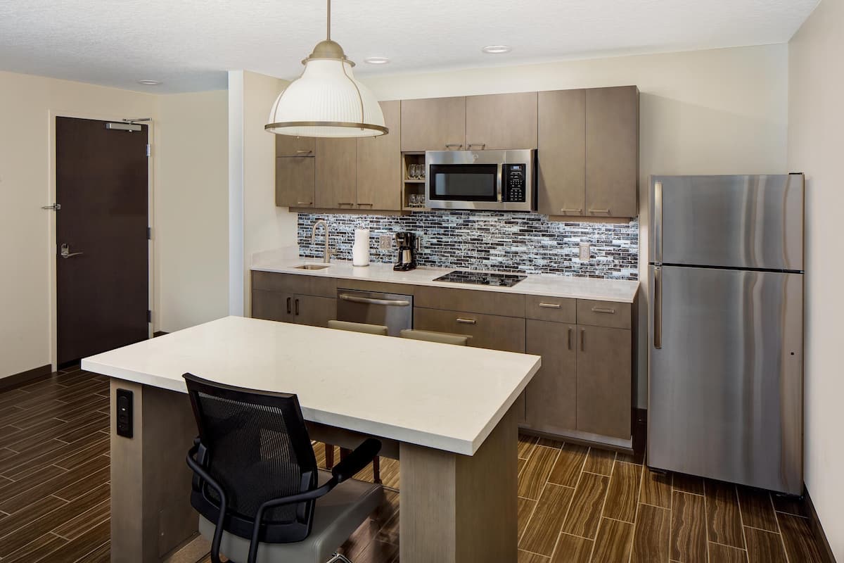 A modern kitchen with a central island, stainless steel appliances, and a tiled backsplash.
