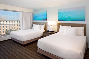 A hotel room with two beds, a nightstand with a lamp, and a large window with curtains. - Hyatt House across from Universal Orlando Resort (Orlando)