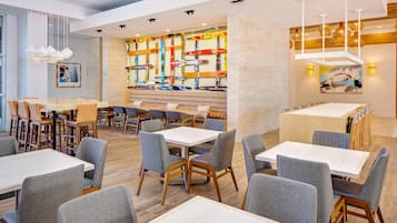 Interior de restaurant modern amb diverses zones de menjador, taules i cadires de fusta.