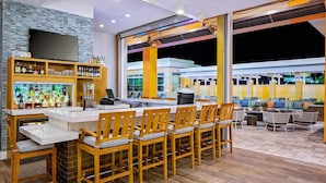 A bar area with a counter, multiple chairs, and a variety of bottles and glasses on shelves.