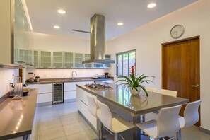 Une cuisine moderne dotée d’un îlot central, de meubles blancs et d’une hotte en acier inoxydable.