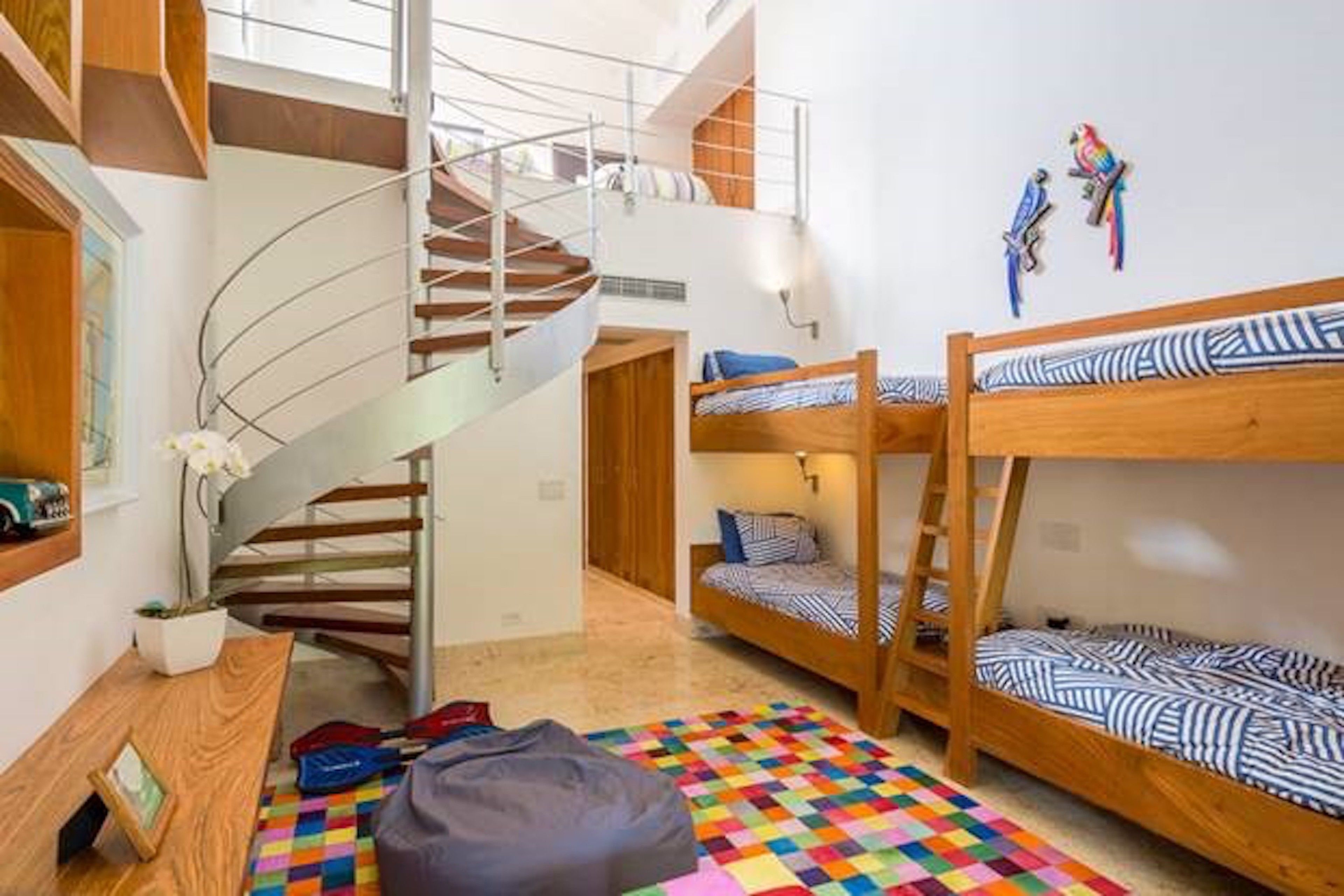 A multi-level room with bunk beds, a spiral staircase, and a colorful checkered floor.
