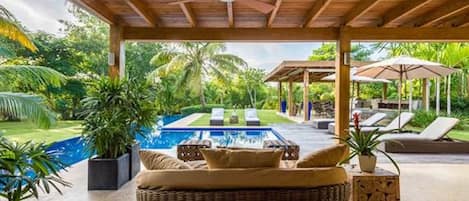 Una piscina al aire libre, sombrillas, sillones reclinables de piscina