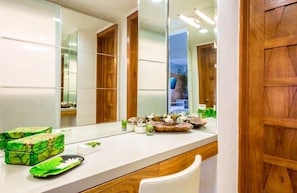 Un baño con encimera blanca, un espejo grande y armarios de madera.