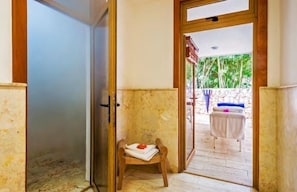 Una puerta abierta que da a un balcón con una pequeña silla de madera y una mesa.