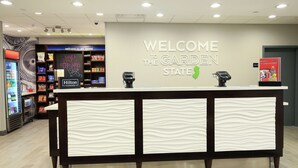 A reception desk with a 'Welcome to the Garden State' sign, a Hilton Honors sign, and a digital kiosk.