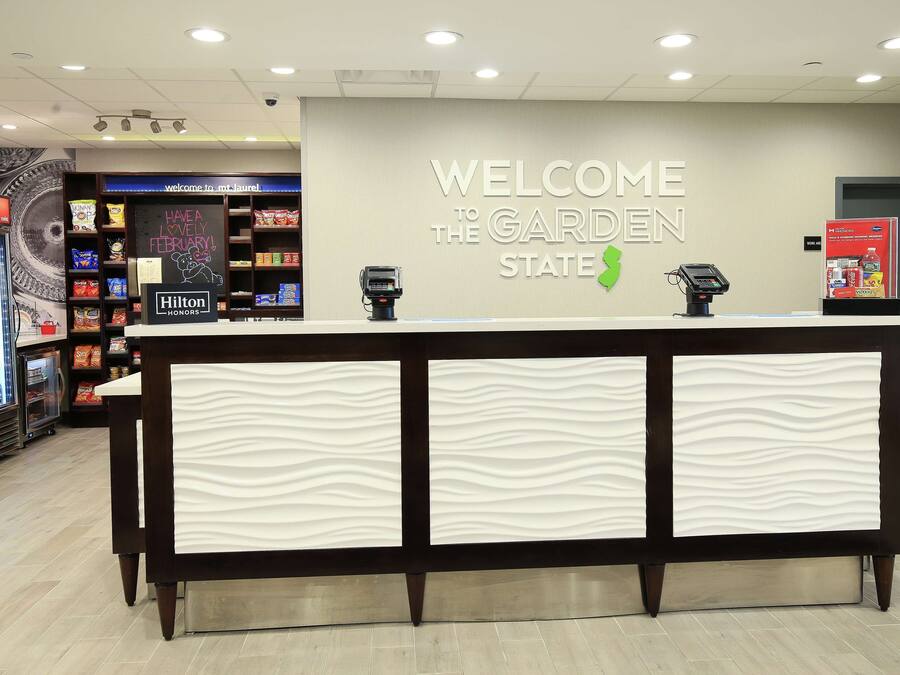 A reception desk with a 'Welcome to the Garden State' sign, a Hilton Honors sign, and a digital kiosk.