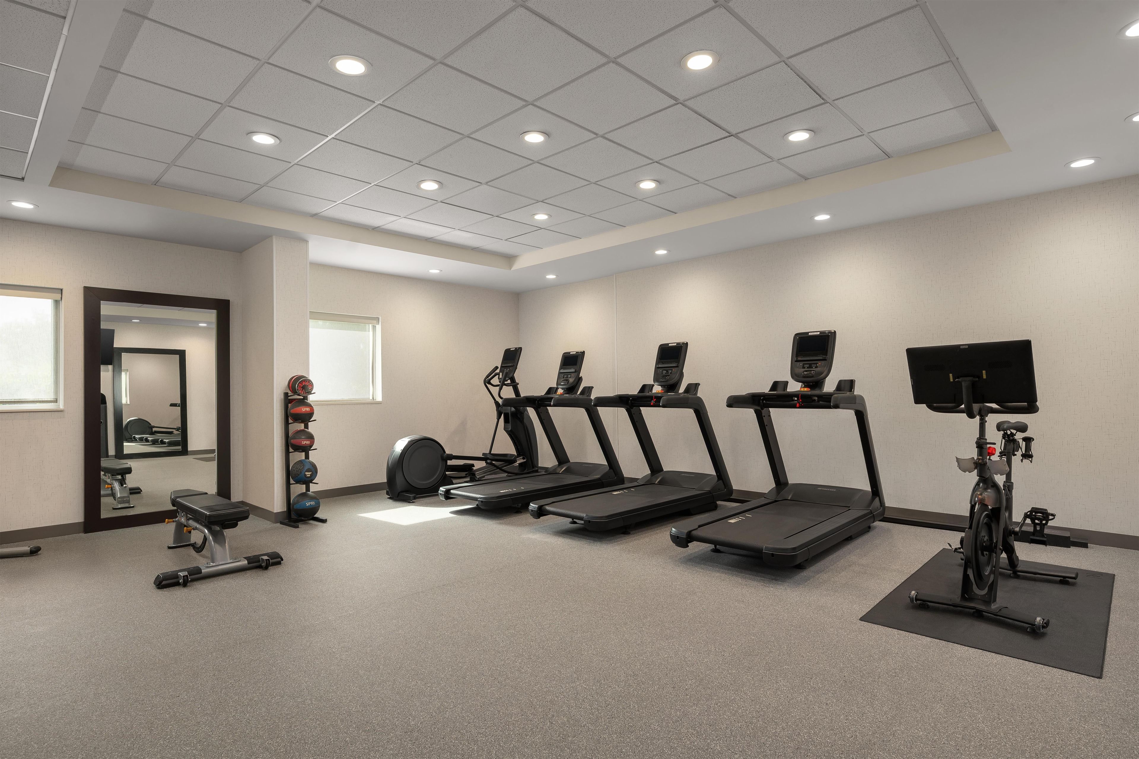 A fitness room with treadmills, a stationary bike, and a weight bench.