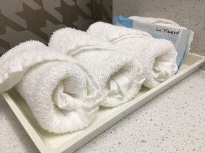 A white tray with neatly folded towels and a travel-sized La Fresh towel set.